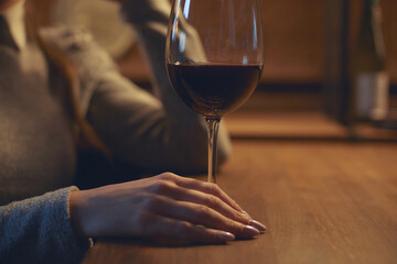 Hand of a young beautiful woman holding a glass of wine indoors of a stylish wine restaurant