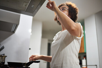 Obraz premium Woman cooking with a frying pan on the stove