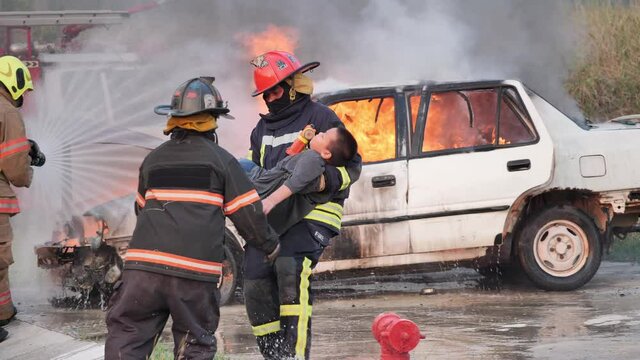 Asian fireman wear fire protection suit while saving a boy from a car accident. Training fire drill and helping fire victims car accident Slow Motion
