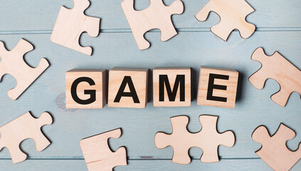 Blank puzzles and wooden cubes with the GAME lie on a light blue background.