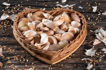 Garlic Cloves and Bulb in Heart Basket on Rustic Wooden Background.