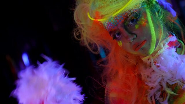 extravagant makeup and image for artistic performance, fluorescent paint on face and body of woman