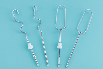 Metal chrome beaters for whipping cream and dough with a mixer on turquoise background.