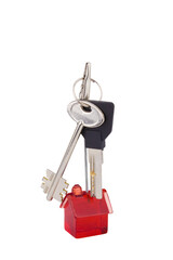A red, transparent, plastic toy house and two keys to the apartment. Isolated on white background. Real estate market, mortgage and trade symbol. A bunch of keys hangs on a clip above the house