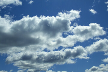Thunderous dark dramatic cumulus white clouds against the blue sky. Blue sky with clouds, free space. The background. The sun shines through the clouds. weather. Frame of clouds around the blue sky
