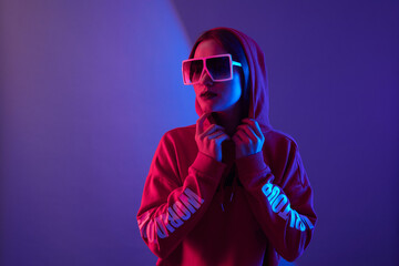 Fashion young woman model wear hoodie and eyewear sunglasses in neon light studio background.