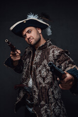 Elegance pirate with pistols posing against dark background