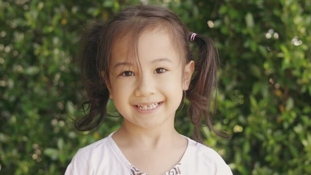 Half body 4k for adorable 5 years old asian with black hair girl posing and acting with smiling to camera on green plant background shows joyful and cheerful emotion expression for environment.