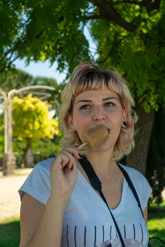 chica joven comiéndose un helado en el parque , chica de pelo corto y ojos claros con un helado en la mano