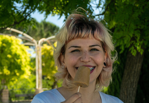 Chica feliz con un helado en la mano en el parque, chica con Brackets  comiendo un helado