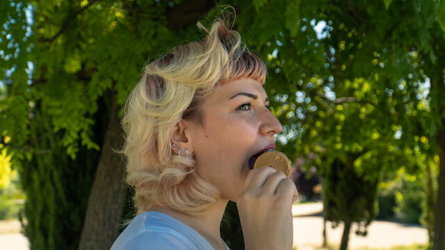 chica joven comiéndose un helado en el parque , chica de pelo corto y ojos claros con un helado en la mano