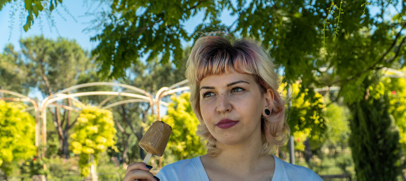 Chica pensativa con un helado en la mano, chica de labios rojos y flequillo comiendo un helado