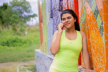 Fototapeta premium Hispanic young woman talking on cell phone in a park