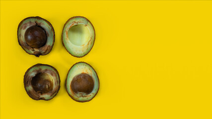 Two bad avocado. Ugly food on yellow background. Rotten tropical fruits. Concept of rotten fruit. Copy space on yellow background.