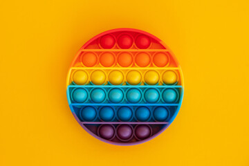 Antistress pop it toy. New popular silicone colorful antistress popit toy for child on yellow background. Top view. Copy space for text.