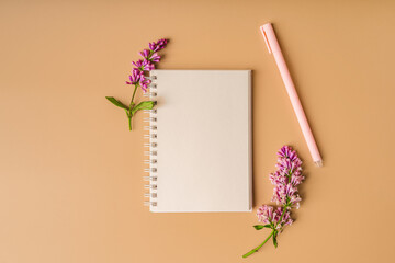 A workspace with note paper and a lilac floral composition. Beautiful spring background with space for text, top view