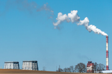 Fototapeta na wymiar View of a thermal power plant or a factory for the production and processing of petroleum products. Large industrial chimneys against a clear blue sky. Removal of combustion