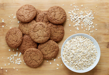 Healthy oatmeal cookies and oat flakes in bowl on wooden backgro