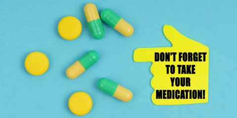 On a blue background, there are pills and a hand-sticker with the inscription - Don t forget to take your medication