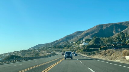 Fototapeta premium MALIBU, CA, DEC 2020: view looking north, driving on Pacific Coast Highway 1 with the Pacific Ocean on left