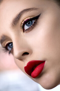 Portrait of beauty model with bright color red lip makeup and creative arrows on eyes. Beautiful young woman with professional make up and long eyelashes Close up, Selective focus