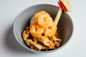 Bowl with shrimps and mushrooms on bright background