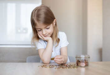 Obraz na płótnie Canvas Kid saving money putting coins into glass bank, Concept finance business investment, money saving.