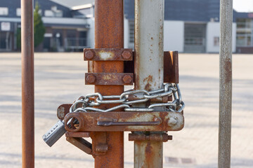 Locked rusty metal fence with chain and padlock combination lock. Closed borders immigration or lockdown concept. Image with selective focus.