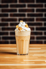 Iced coffee cafe latte with cream and caramel popcorn on bright table, coffe shop.