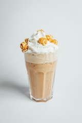 Iced coffee cafe latte with cream and caramel popcorn on bright table, coffe shop.