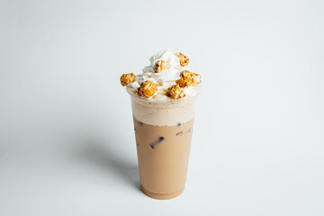 Iced coffee cafe latte with cream and caramel popcorn on bright table, coffe shop.