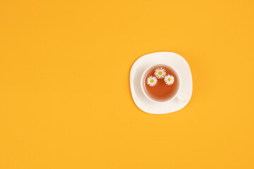 Cup of tea with flowers isolated on yellow background top view with copy space for text
