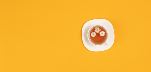 Cup of tea with fresh flowers on yellow background. Top view. Copy space.