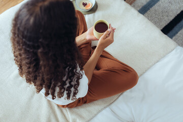 Schwarze Frau trinkt einen Tee im Bett