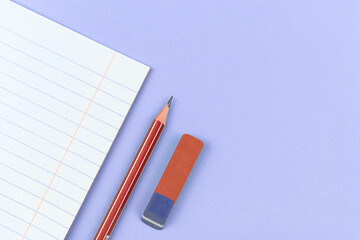 School notebook with pencil and eraser school composition backgorund on a purple office table