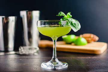 Thai Basil Gimlet Cocktail with Garnish: A gin cocktail in a coupe glass - obrazy, fototapety, plakaty