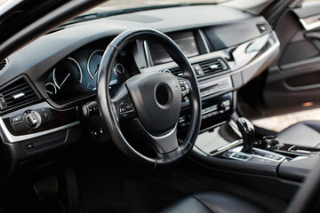 Luxury modern car Interior. Steering wheel, black leather seats, shift lever and dashboard. Detail of modern car interior.