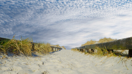 Fototapeta na wymiar Low angle photograph of a path to the beach on a day with cloudy sky
