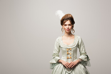 smiling woman in elegant vintage dress looking at camera isolated on grey