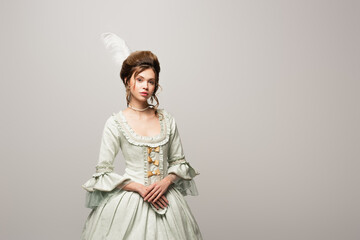 pretty woman in elegant vintage dress looking at camera isolated on grey