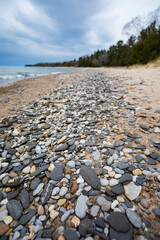Fototapeta na wymiar Stones scattered on sandy beach along Lake Michigan shoreline.
