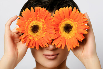 Woman smiling and holding flowers in front of her eyes.