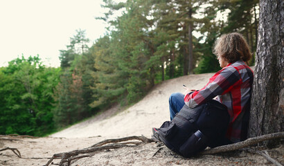 Male tourist with smartphone resting in the woods.