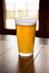 Frosty cold glass of beer on wooden table.