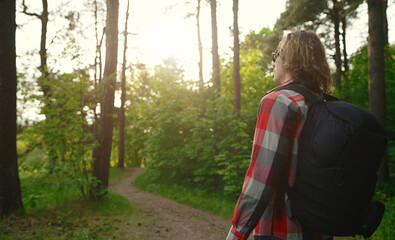 Man with backpack and sunglasses in the woods. Arc shoot.