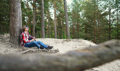 Male tourist with smartphone resting in the woods.