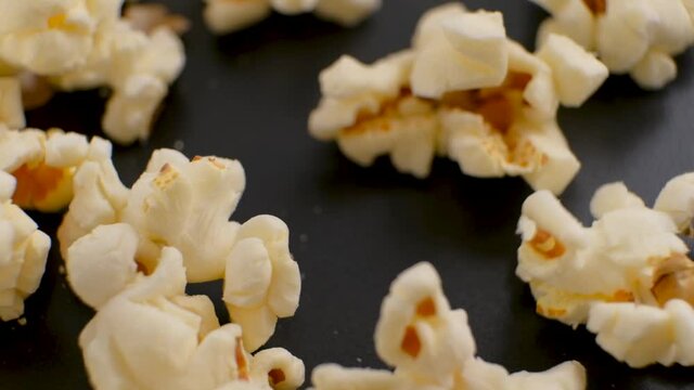 Fresh popcorn fall down to the black plate in Slow Motion