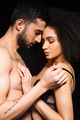 Shirtless man taking off bra from african american woman isolated on black