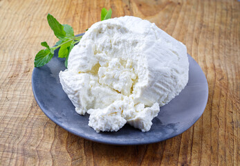 Fresh Italian ricotta with mint leaves served as close-up on a modern design plate with copy space