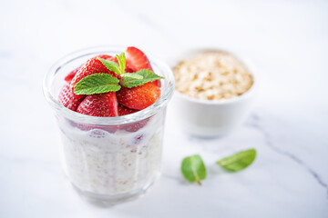 Oatmeal porridge with milk and fresh strawberries in a glass